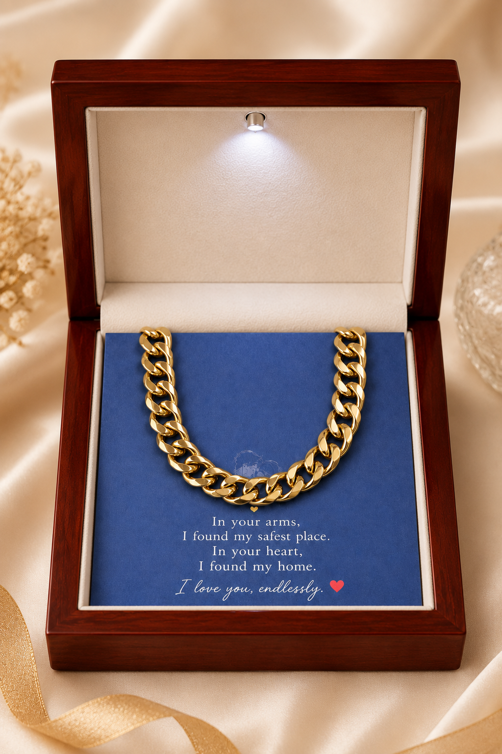 A gold Cuban link chain necklace presented in an open wooden gift box with a blue insert card that reads 'In your arms, I found my safest place. In your heart, I found my home.