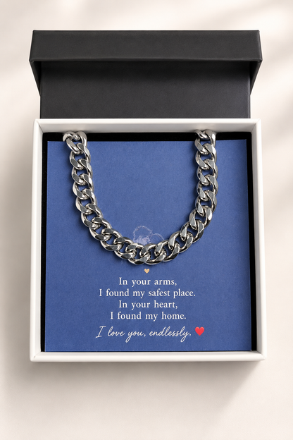 A silver Cuban link chain necklace presented inside an open white gift box with a black lid, set against a blue card with a sentimental message printed on it.