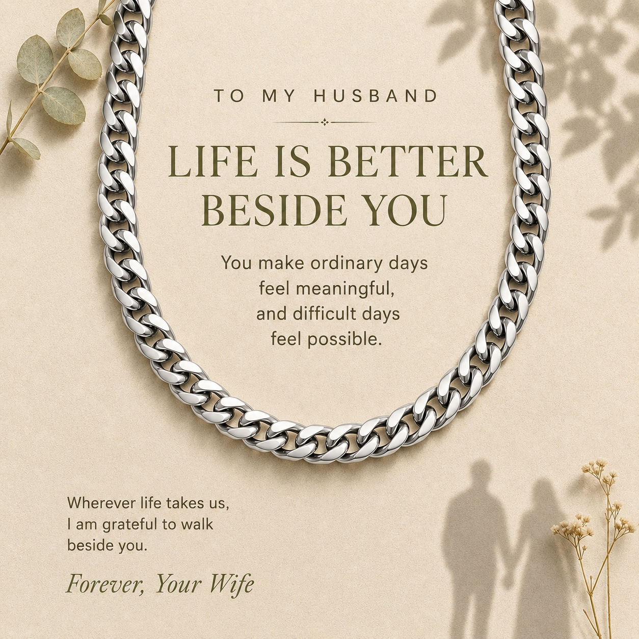 A silver curb chain necklace arranged in an oval on a warm beige background with printed sentimental text for a husband and decorative dried leaves and shadow overlays.