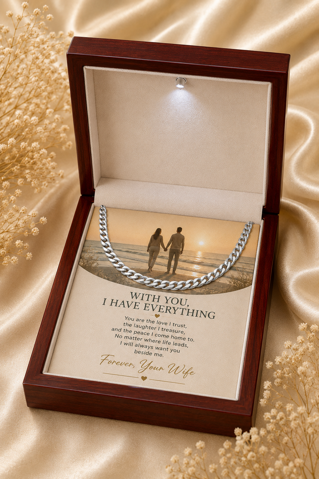 An open dark wood keepsake gift box with a beige interior, displaying a silver chain necklace over a printed message card that reads 'WITH YOU, I HAVE EVERYTHING' and 'Forever Your Wife.' The box is photographed on a satin-like beige fabric with small dried floral props around it.