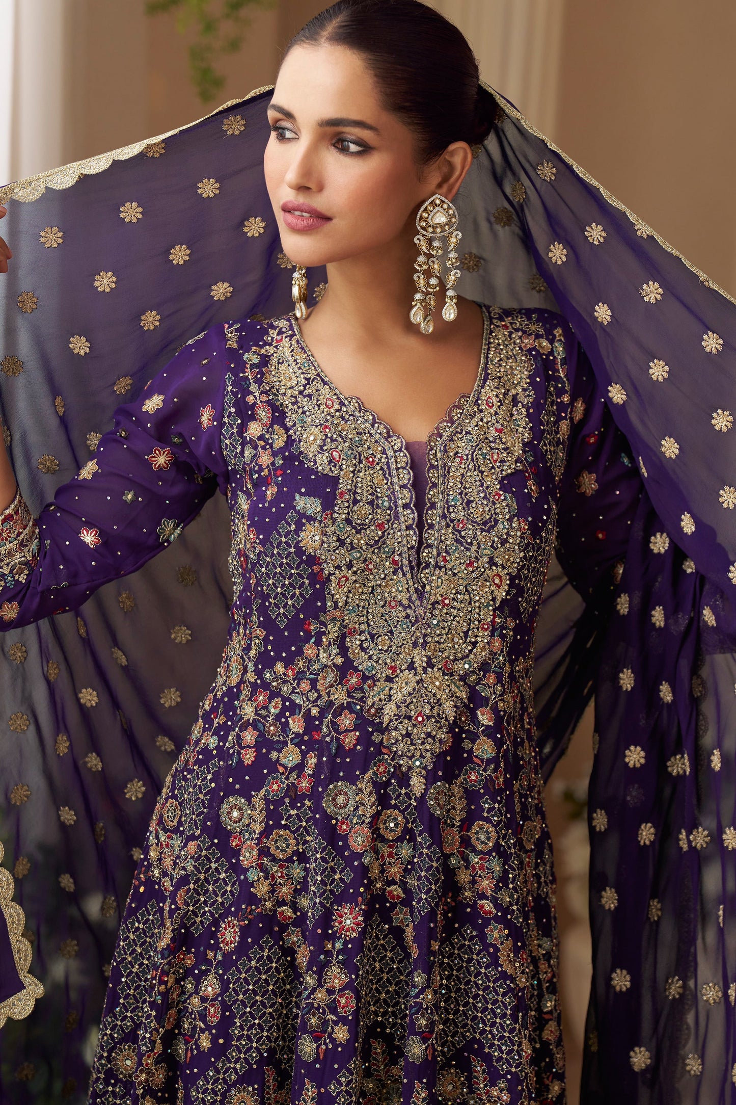 Woman in a purple embroidered traditional outfit with a sheer dupatta.
