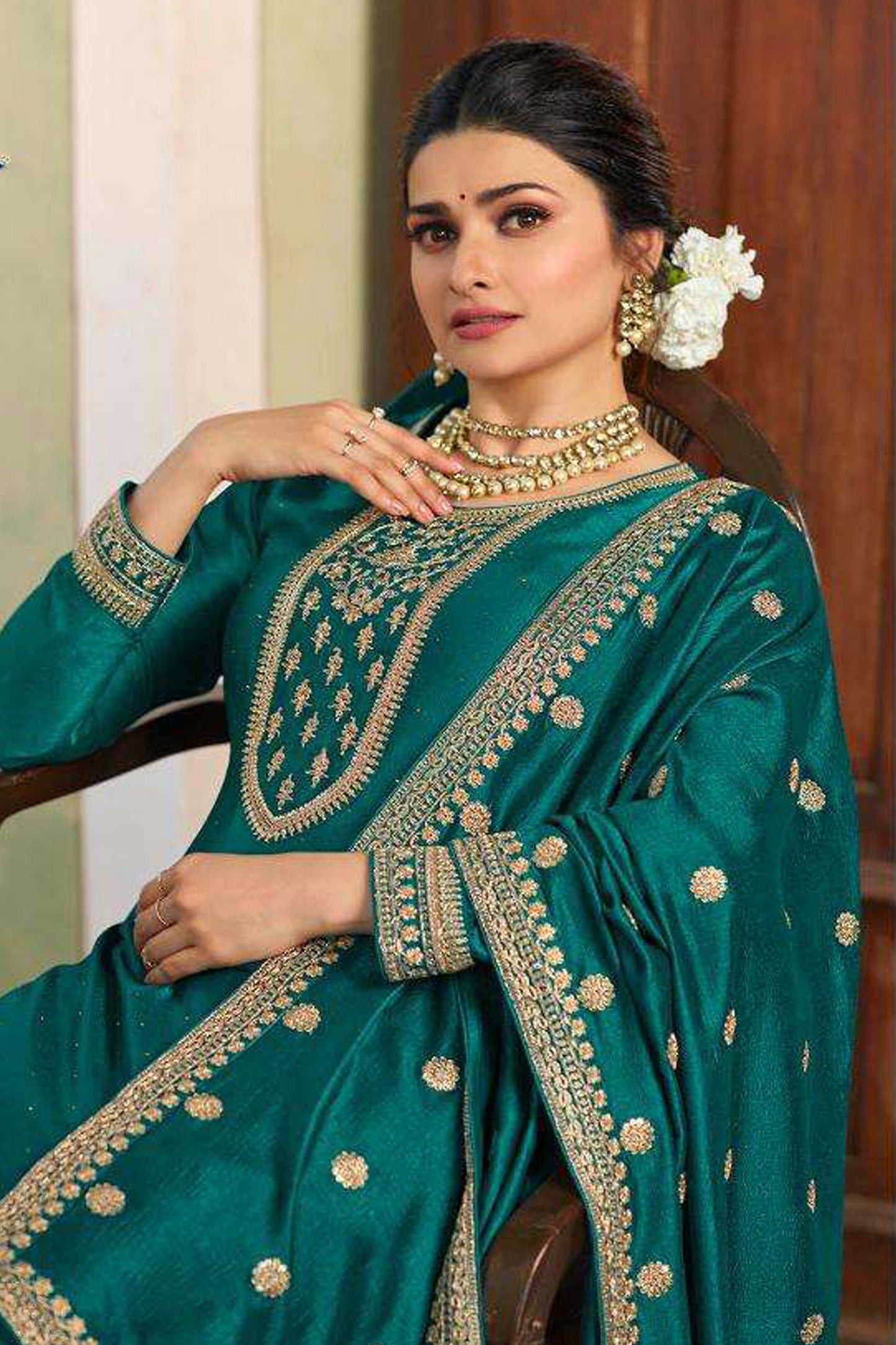 A Woman Standing Traditional Indian Setting, Wearing a Green Embroidered Palazzo Suit