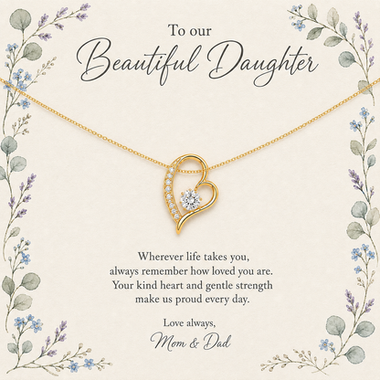 A gold heart-shaped pendant necklace with a clear central gemstone, displayed on a cream-colored memorial card with floral borders and the text 'To our Beautiful Daughter' and 'Love always, Mom & Dad'.
