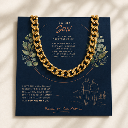 A gold chain necklace draped over a navy blue gift card with sentimental text and illustrations, photographed on a light beige surface with soft shadows.