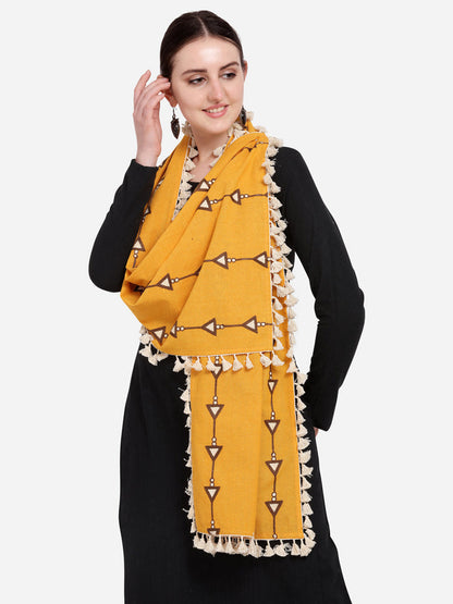 Woman wearing a mustard yellow scarf with decorative patterns on a plain background