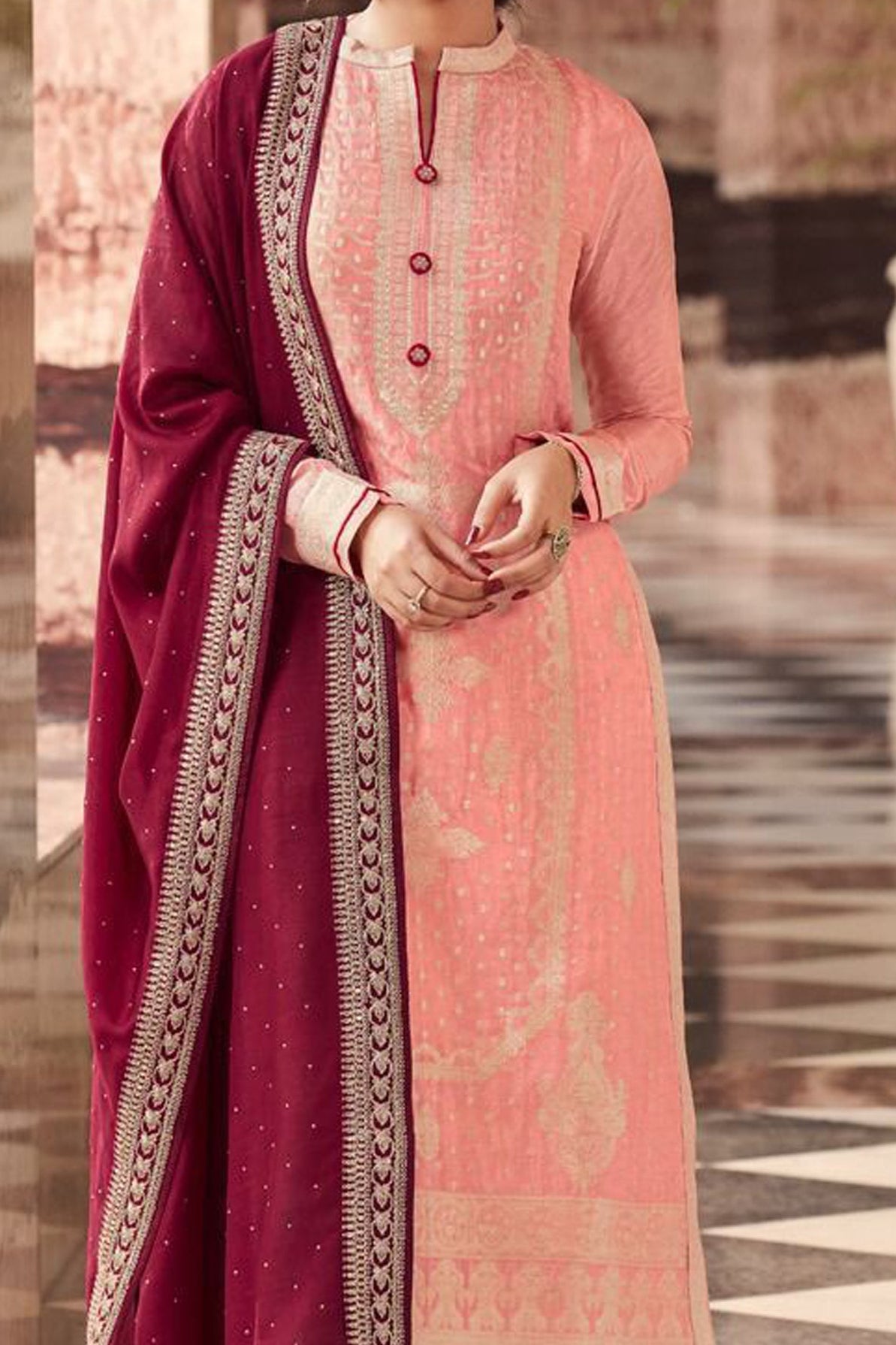 Woman in traditional pink and maroon outfit standing on a checkered floor.