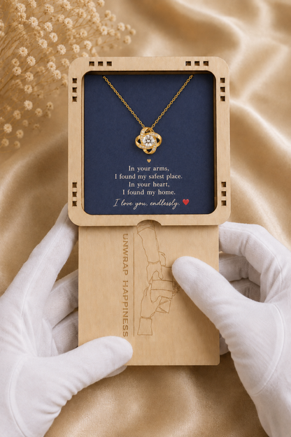 Gold-tone knot necklace with clear centre stone presented on a navy love message card in an elegant open gift box.