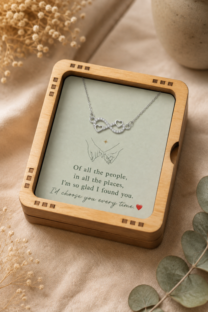 Silver-tone infinity heart necklace displayed inside natural wooden presentation box