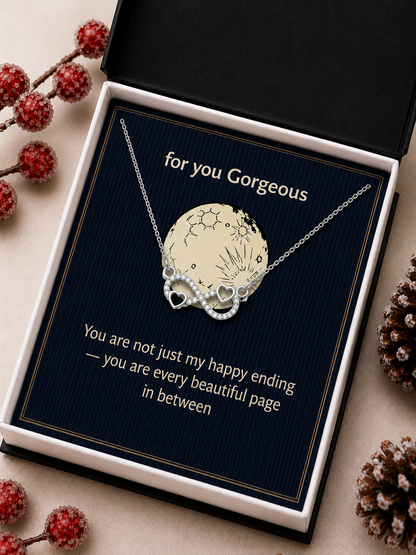 Silver-tone infinity heart pendant displayed on a dark blue velvet-style card