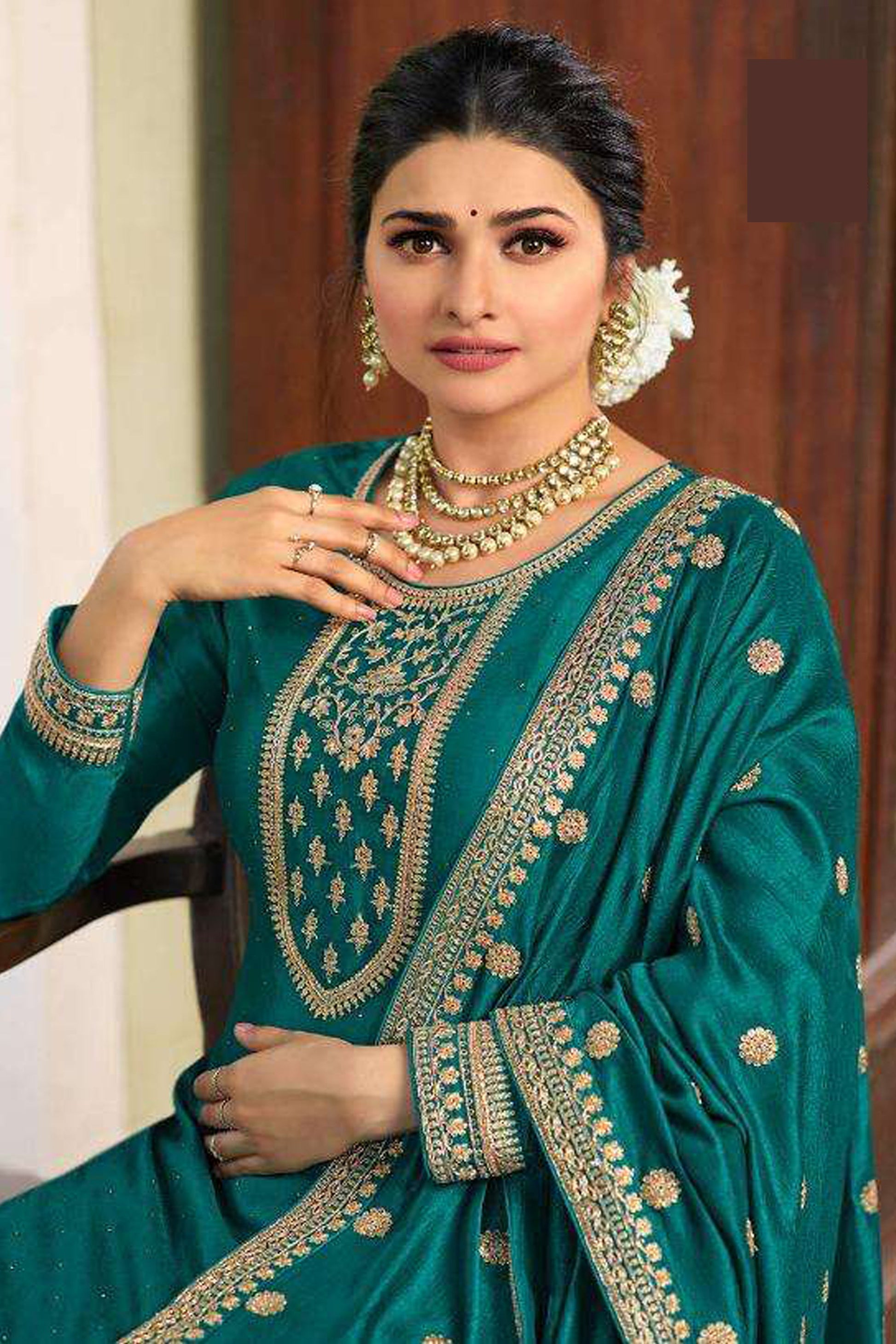 A Woman Standing Traditional Indian Setting, Wearing a Green Embroidered Palazzo Suit