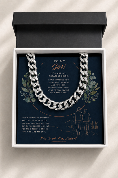 A silver chain necklace presented inside an open white gift box with a black lid, set against a light neutral background. 