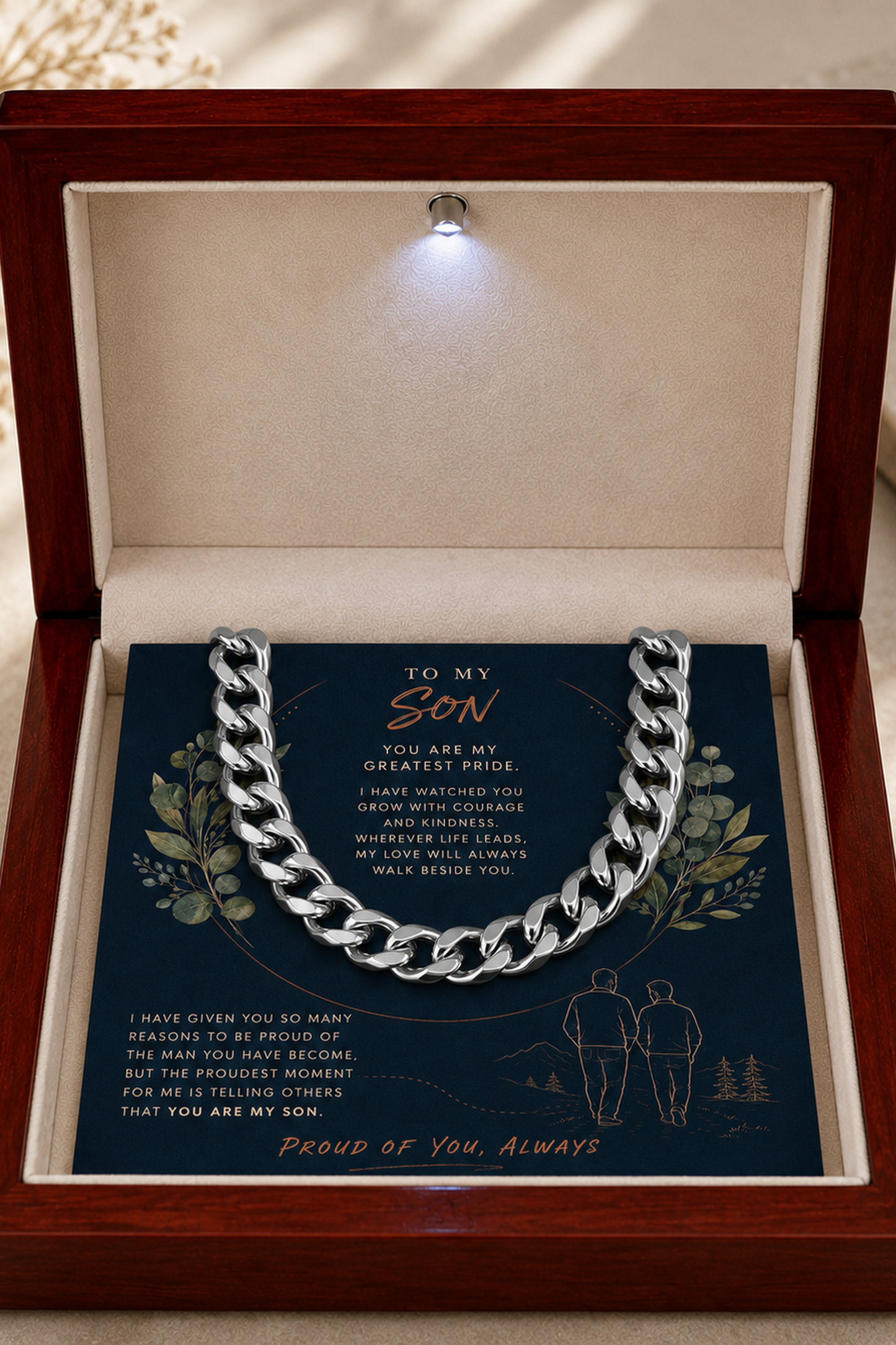 A silver chain necklace presented inside an open wooden gift box with a soft cream interior. 